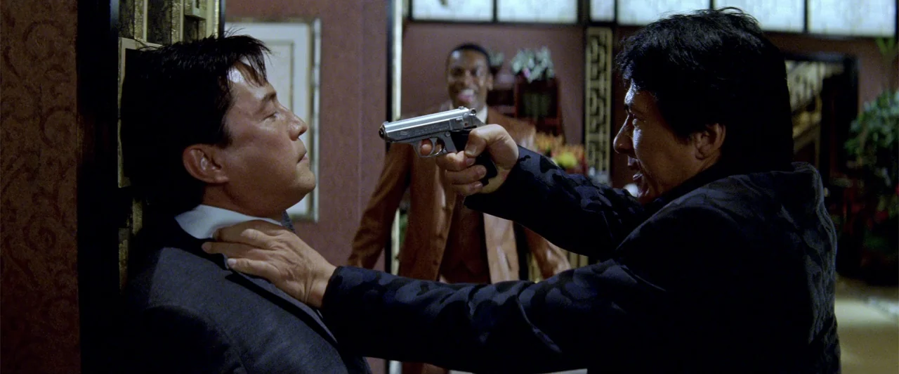 Rush Hour 2 (2001) movie still: medium — A dimly lit room with textured dark walls and intricate wood trim details. One man holds another against a…