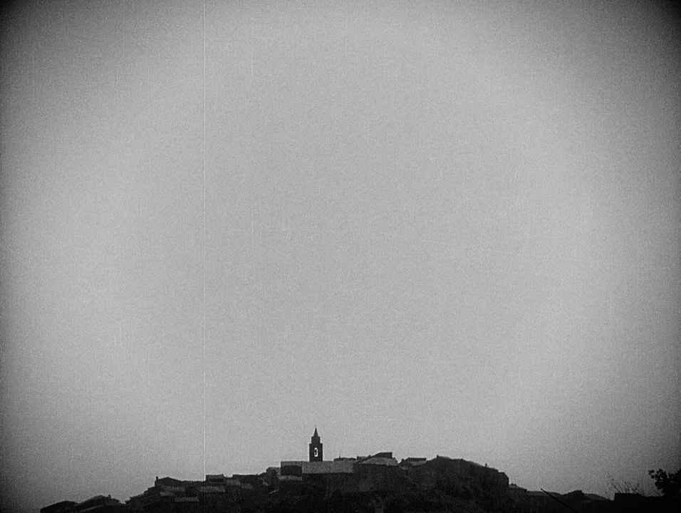 Coeur Fidele (1923) movie still: establishing — A remote hillside village with a prominent central bell tower stands against a sky. The entire…
