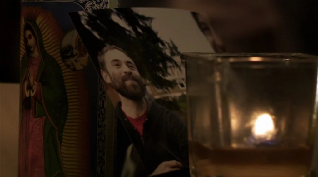 Your Sister’s Sister (2011) movie still: closeup — A close-up shows a photograph propped next to a candle in a glass holder. To the left of the…