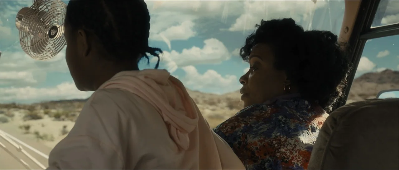 King Richard (2021) movie still: medium — Inside a vehicle traveling through a bright, arid desert landscape with clear skies. Two women sit in the…