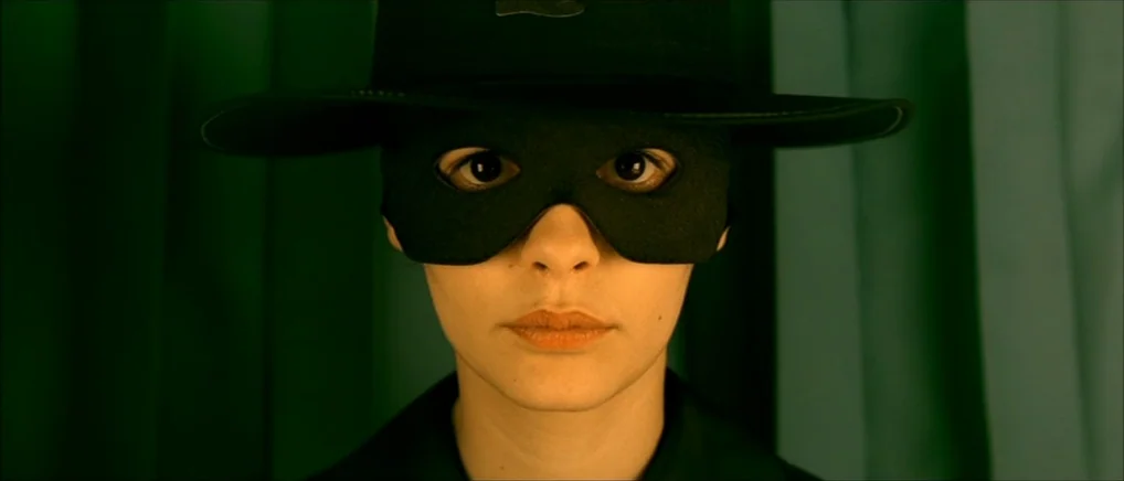 Amelie (2001) movie still: closeup — A person stands centered before a bright green fabric background. The subject wears a black wide-brimmed hat…