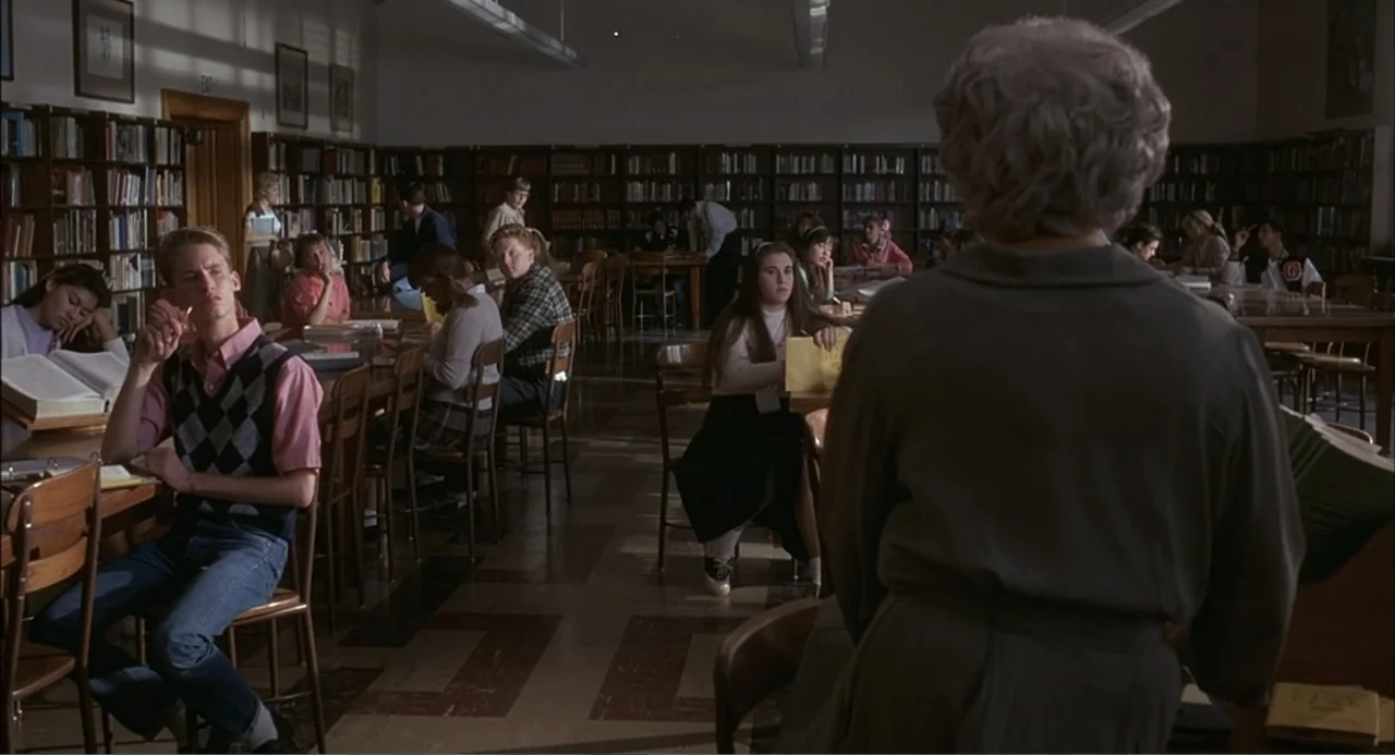 Wild Orchid II: Two Shades of Blue (1991) movie still: medium — A quiet school library with rows of bookshelves and students studying at wooden…