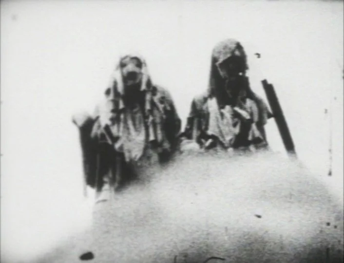 Begotten (1989) movie still: medium — Two figures stand together in a bright, desaturated, and grainy outdoor environment. The subjects remain…