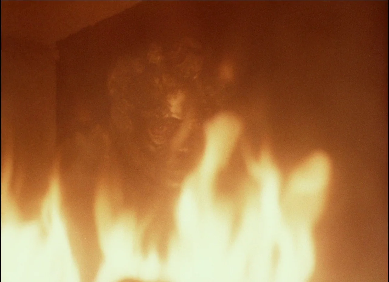 Beauty and the Beast (1979) movie still: closeup — A dark indoor space is filled with intense flickering flames in the foreground. A man stands…