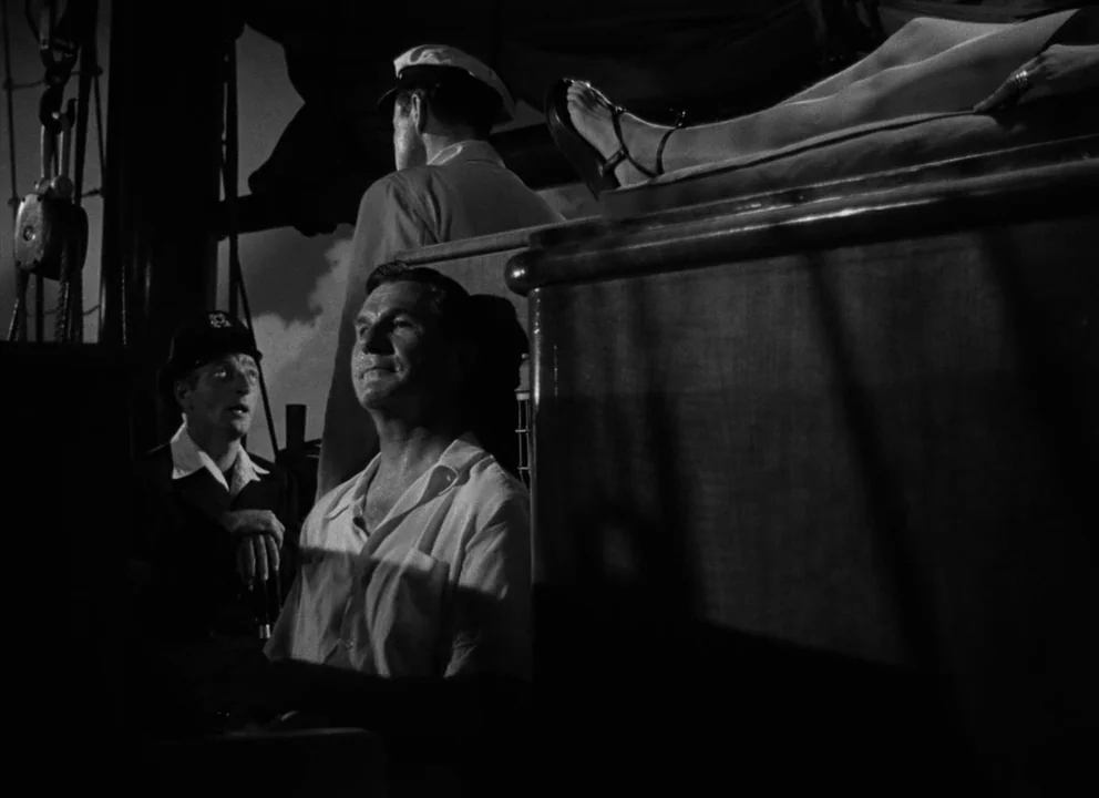 The Lady from Shanghai (1947) movie still: medium — The deck of a ship at night features several people in uniform. Three men are gathered together…