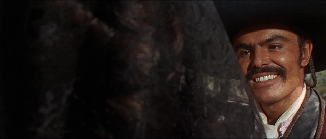The Appaloosa (1966) movie still: closeup — An outdoor setting is dominated by a dark translucent lace veil in the foreground. A man wearing a…