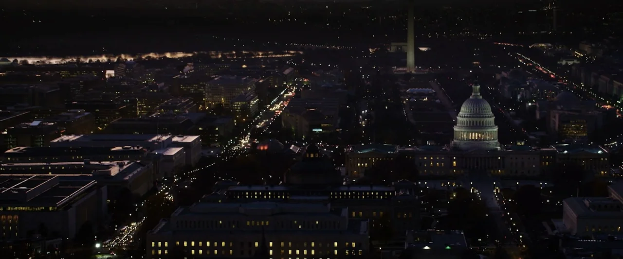 Reagan (2024) movie still: establishing — An aerial nighttime view captures the illuminated buildings of a large metropolitan capital city. The…