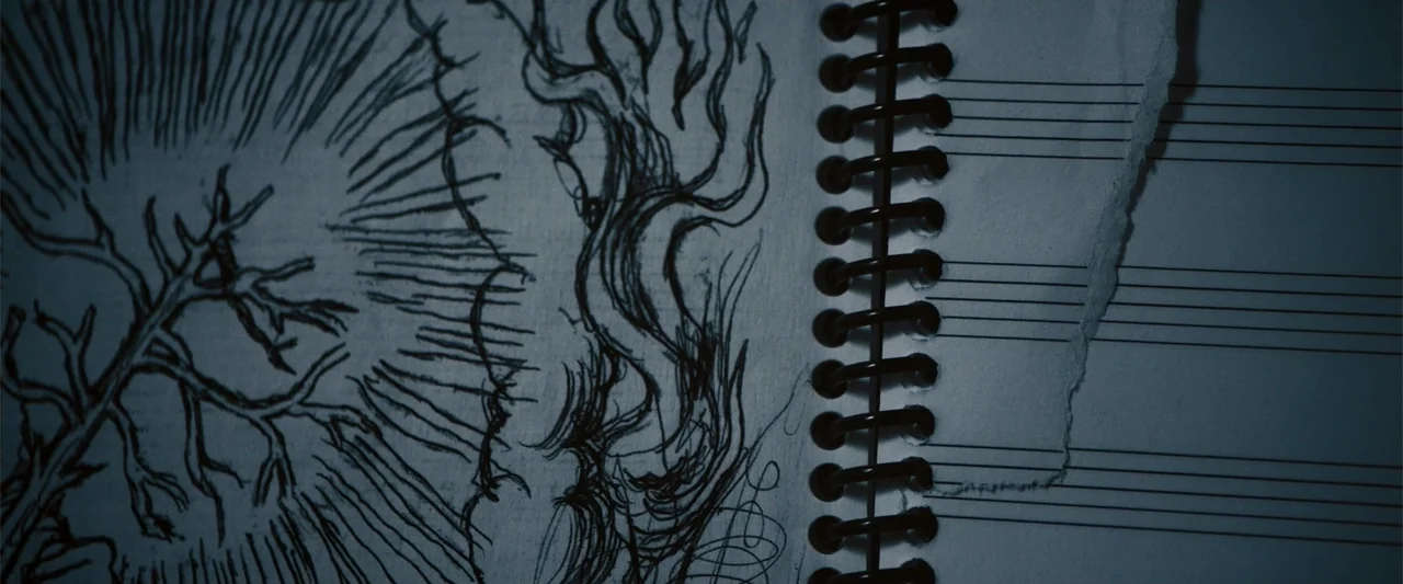 Nocturne (2020) movie still: closeup — A close-up of a spiral-bound notebook with hand-drawn ink illustrations of trees. The page is torn at the…