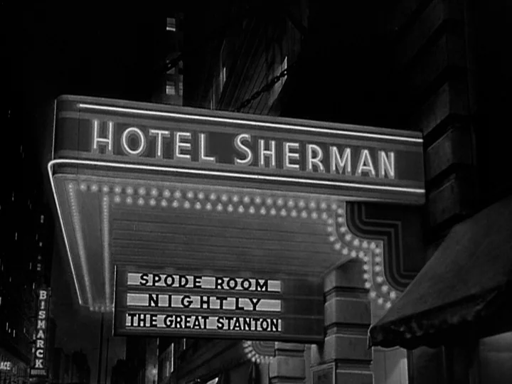 Nightmare Alley (1947) movie still: wide — A night exterior view of a hotel marquee illuminated against a dark city building. The marquee text…