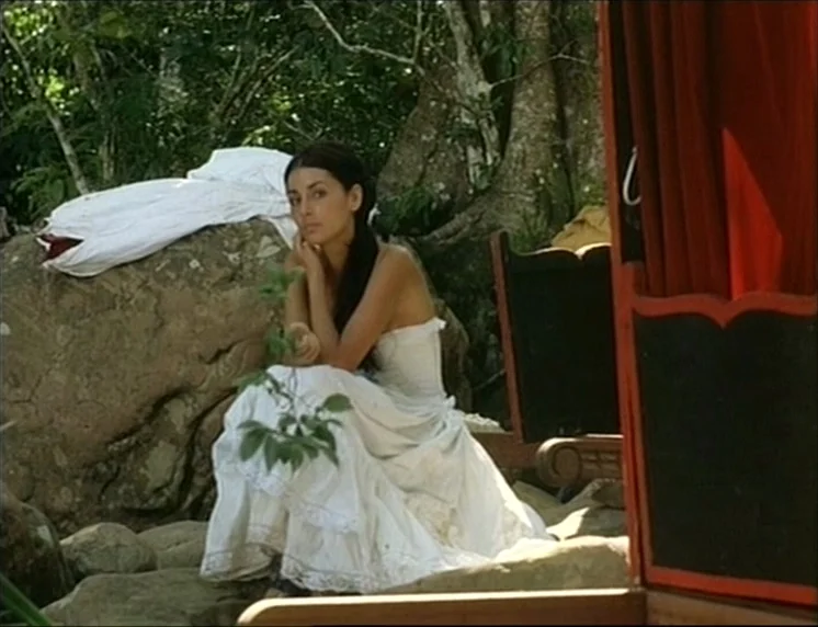 Aguirre, The Wrath Of God (Aguirre, der Zorn Gottes) (1972) movie still: medium — A woman in a white dress sits on a large rock in a clearing. Lush…