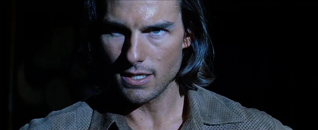 Magnolia (1999) movie still: closeup — A man stands in an undifferentiated dark space with no visible architecture or background elements. The man…