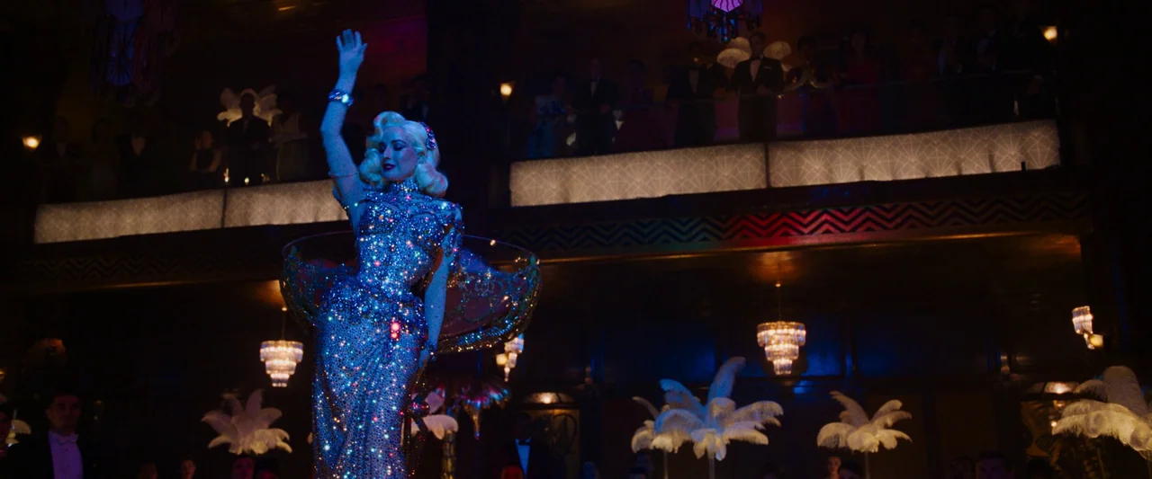 Don’t Worry Darling (2022) movie still: fullbody — A dark, opulent cabaret room features a balcony filled with silhouetted audience members. A…