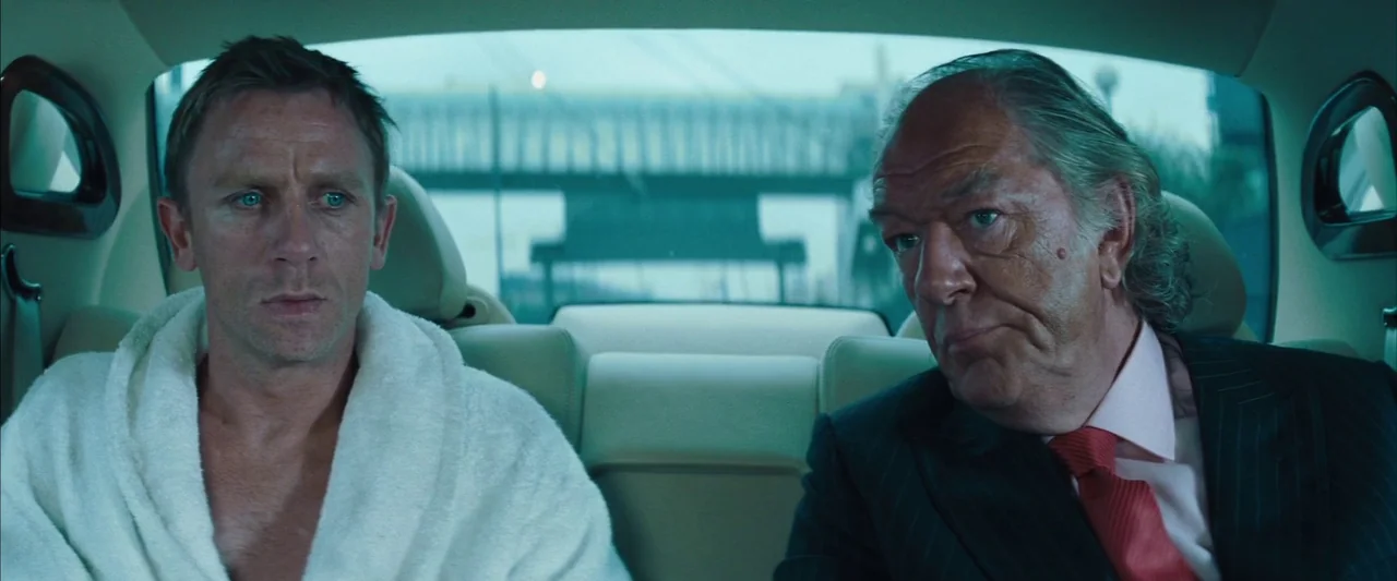 Layer Cake (2004) movie still: medium — The interior of a modern car provides the setting for two men traveling together. A younger man in a…