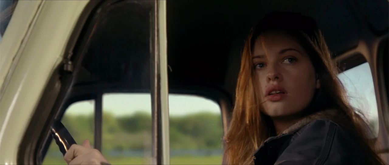 Jeepers Creepers 3 (2017) movie still: medium — The interior of a moving vehicle with a view of green fields visible outside. A woman in a jacket…