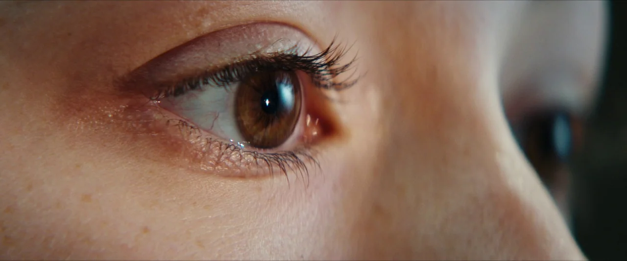 Double Blind (2023) movie still: closeup — A extreme close-up of a human eye. The eye gazes towards the right side of the frame.