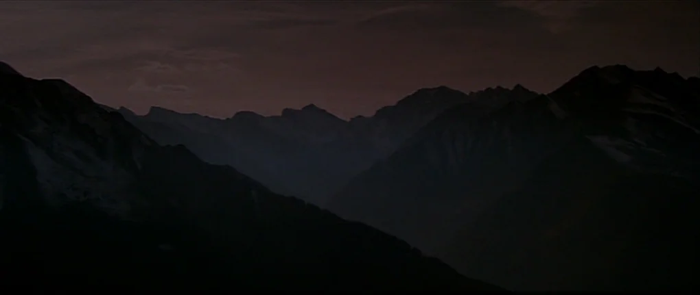 IP5 (1992) movie still: establishing — A vast mountain range stretches across the horizon under a dark twilight sky. The peaks are silhouetted…