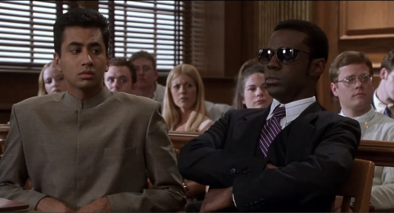 National Lampoon's Van Wilder (2002) movie still: medium — A wood-paneled courtroom filled with seated observers behind wooden benches. A man in a…