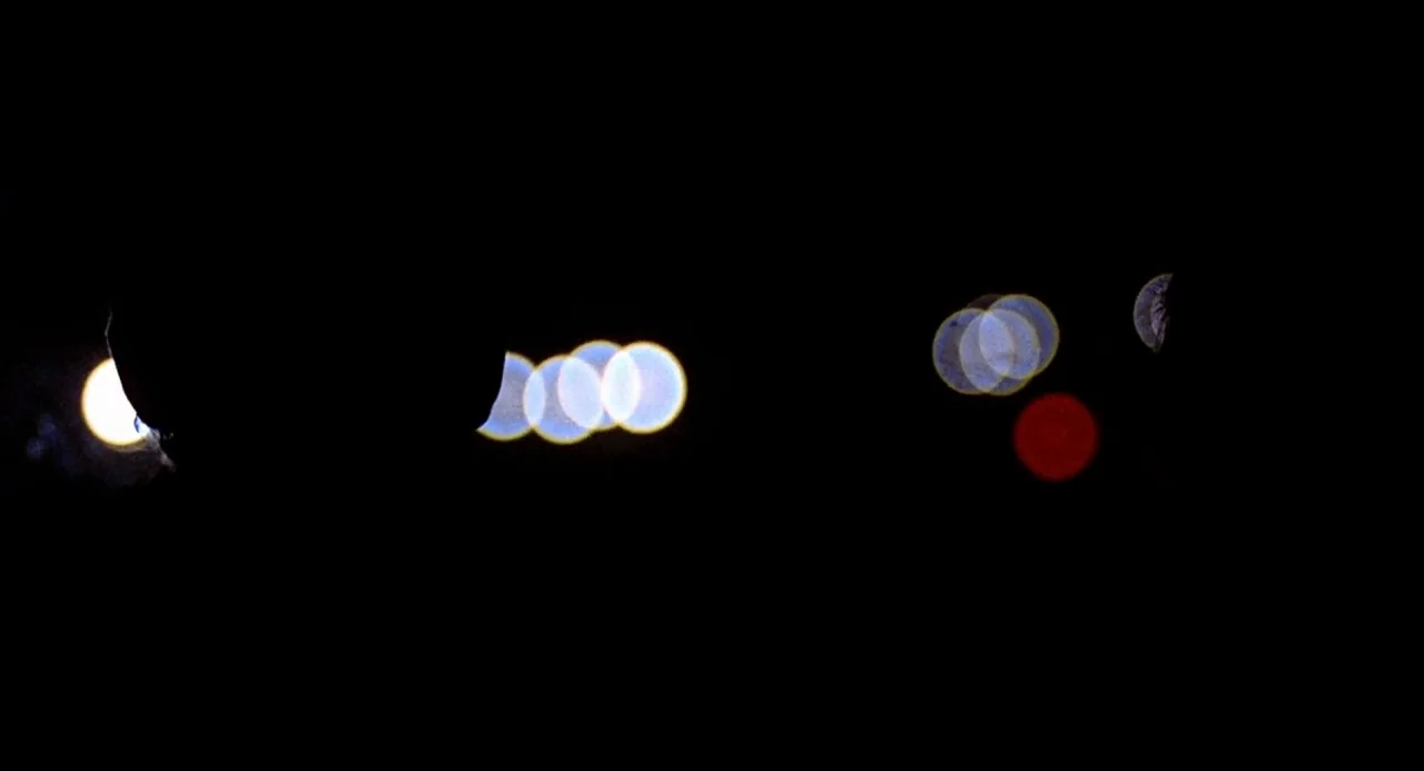 Taking Off (1971) movie still: wide — A pitch-black field is filled with blurry circular lights of various sizes. The lights appear as white, blue,…