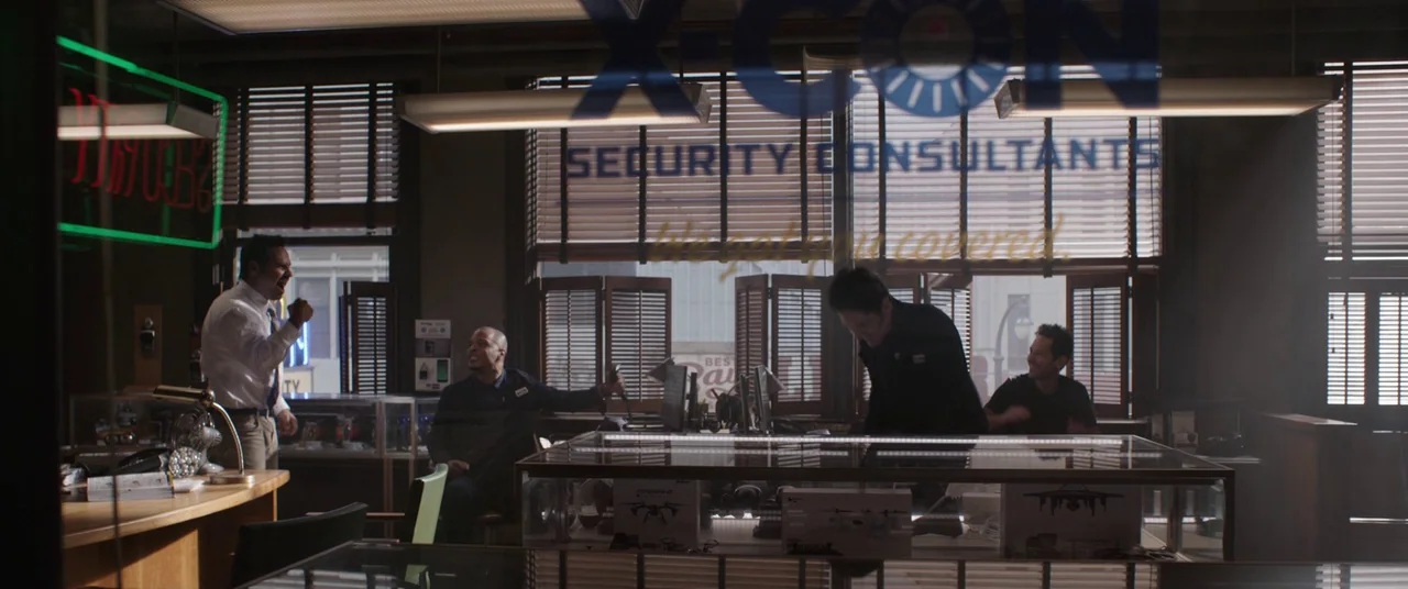 Ant-Man and the Wasp (2018) movie still: wide — A security firm office features display cases with drones and window blinds filtering light. Four…