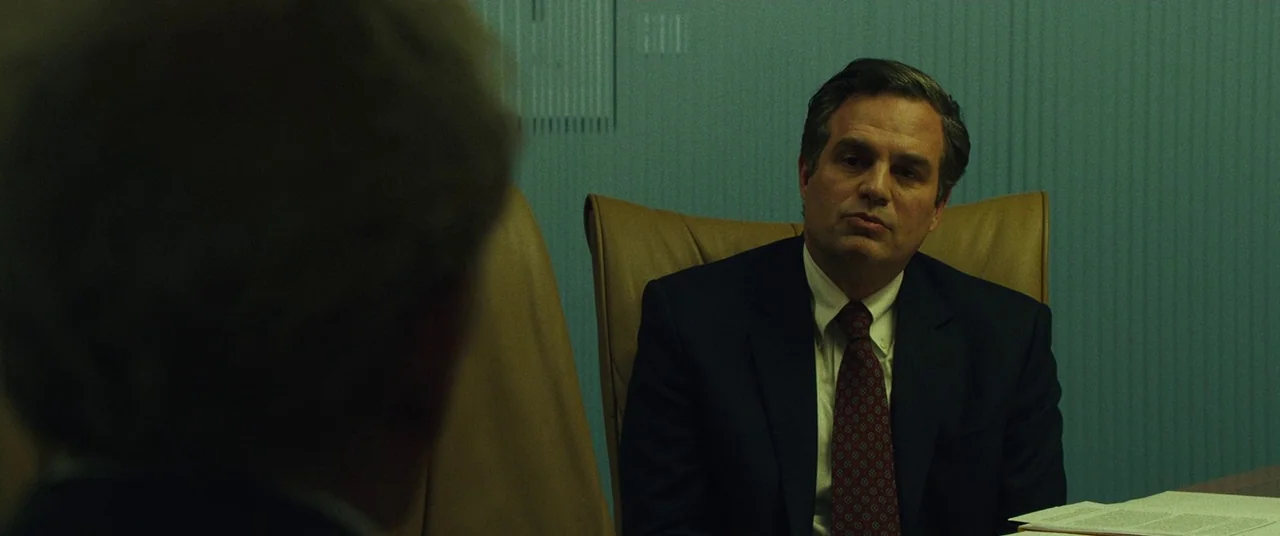 Dark Waters (2019) movie still: medium — A man in a suit sits in a room with teal paneled walls. The subject is seated at a table during a meeting.