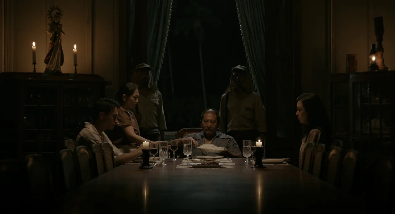 In My Mother’s Skin (2023) movie still: wide — A dark, wood-paneled room features a long table set for a formal family dinner. Several people eat…