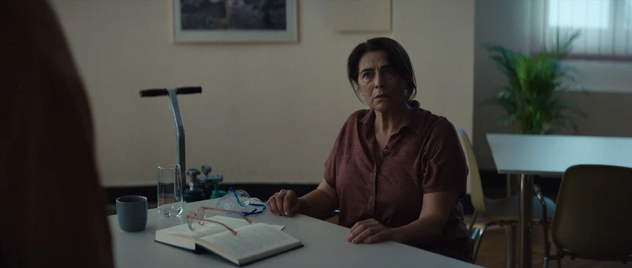 Hellraiser (2022) movie still: medium — A spare, clinical room with a light-colored table holding medical equipment and a book. A middle-aged woman…