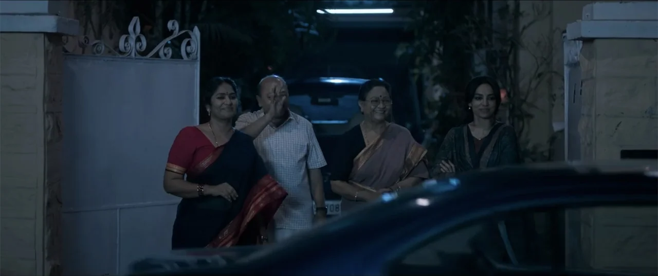 Cheekatilo (2026) movie still: medium — Four adults stand together in a residential driveway at night near a gate. They look toward the foreground…