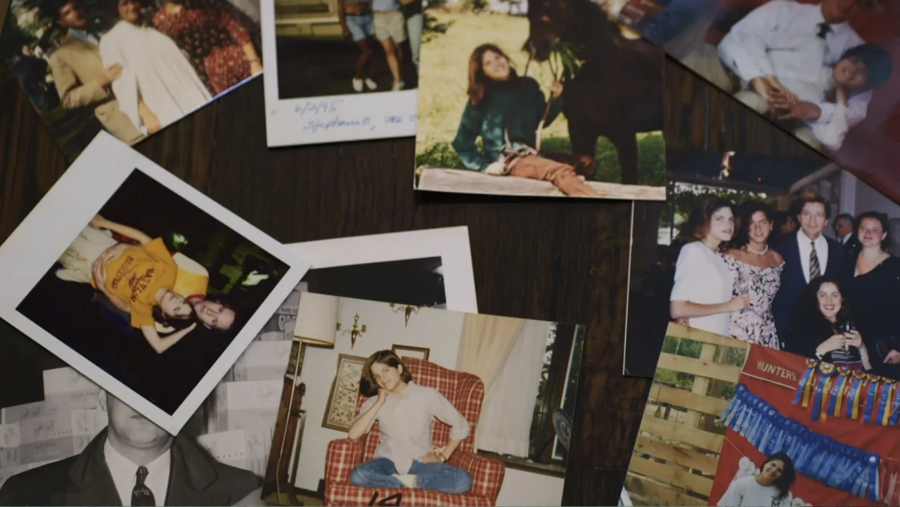 Introducing, Selma Blair (2021) movie still: establishing — A collection of 1990s-era printed photographs lies scattered across a dark wooden table.…