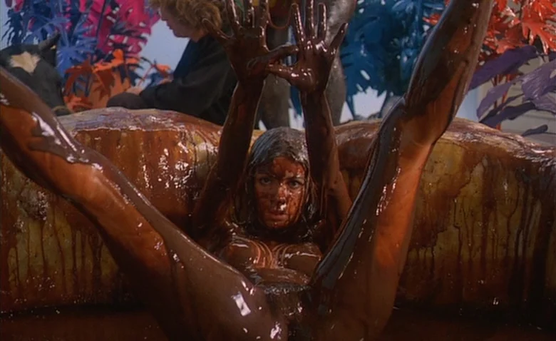 Sweet Movie (1974) movie still: medium — An interior studio setting features a tub filled with thick brown viscous liquid. A woman sits inside the…