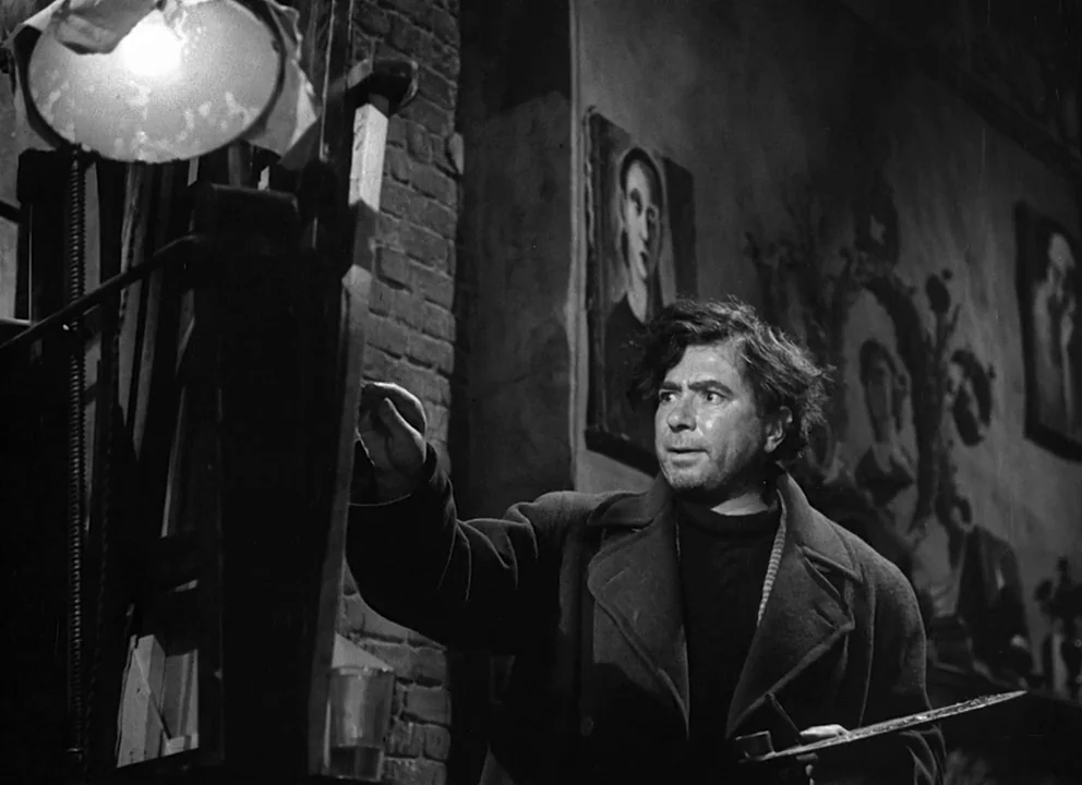 Odd Man Out (1947) movie still: medium — An artist's studio is filled with framed paintings hung on a dark brick wall. A man in a heavy coat paints…