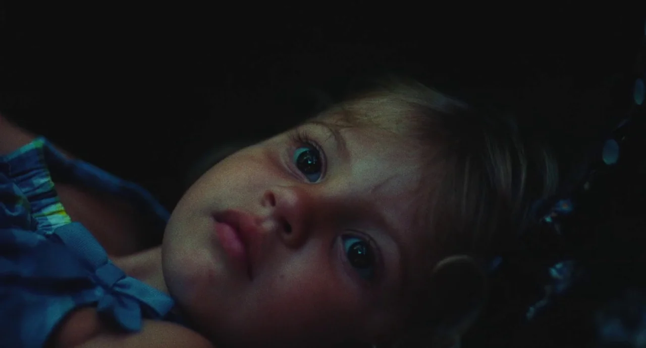 The Giant (2019) movie still: closeup — A child lies in a dark room under low light conditions. The subject gazes upward with eyes wide open.