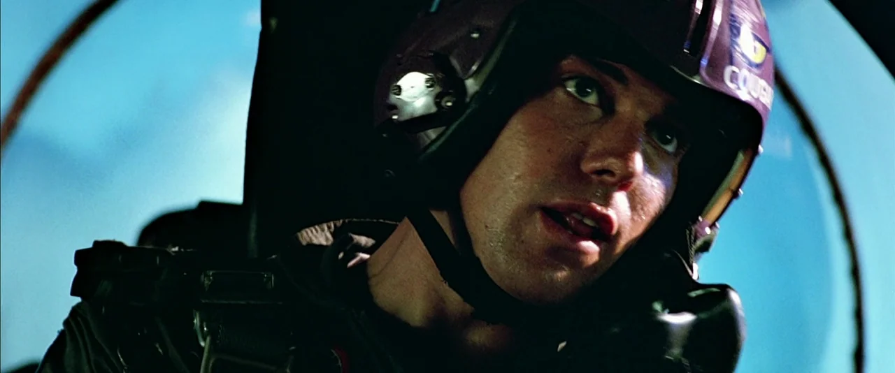 Top Gun (1986) movie still: closeup — The interior of a fighter jet cockpit features blue sky through the glass canopy. A pilot wears a flight…