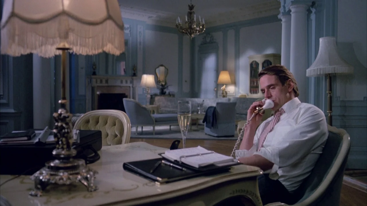 Dead Ringers (1988) movie still: medium — A lavish hotel suite features light blue paneling, crown molding, and antique-style furniture. A man sits…