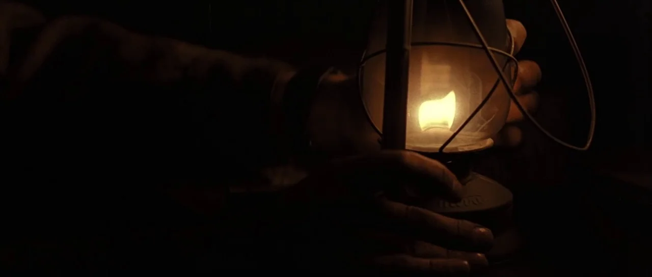 Pink Floyd The Wall (1982) movie still: closeup — A dark, obscured space contains only the intense light of a portable kerosene lantern. Two hands…