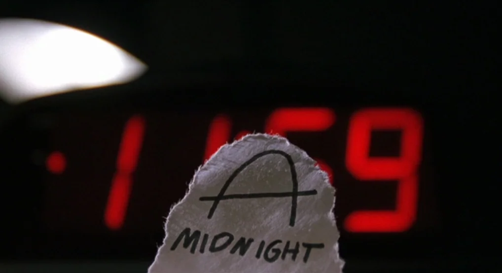 Brick (2005) movie still: closeup — A dark space containing a digital clock showing the time 11:59. A torn piece of white paper with a handwritten…