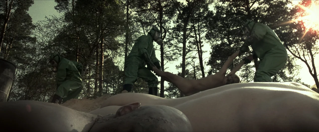 V for Vendetta (2006) movie still: wide — A dense pine wood clearing features scattered sand and large mounds of soil. Three figures in bright green…