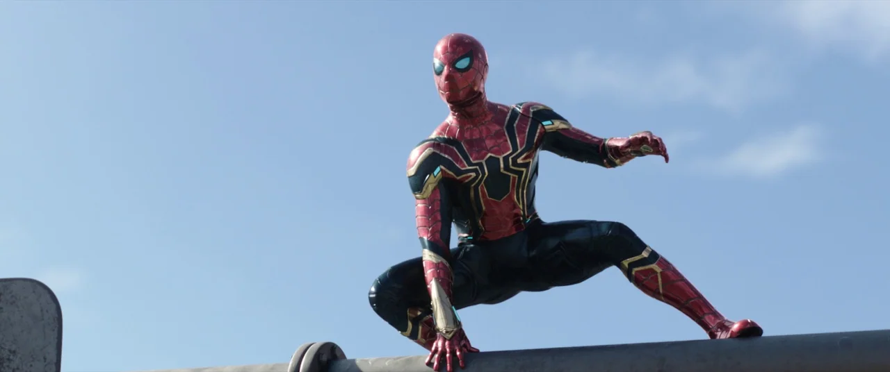 Spider-Man: No Way Home (2021) movie still: fullbody — A figure crouches on a slender horizontal metal pole against a clear blue sky. The subject…