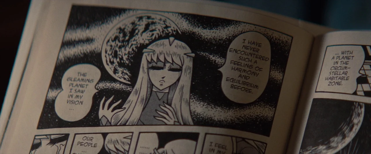 The Spectacular Now (2013) movie still: closeup — A close-up view shows a page from a printed black and white manga. A character with long hair is…