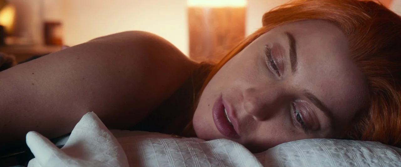 A Star Is Born (2018) movie still: closeup — A person lies on a soft white pillow in a dimly lit space. The individual rests their head on the…