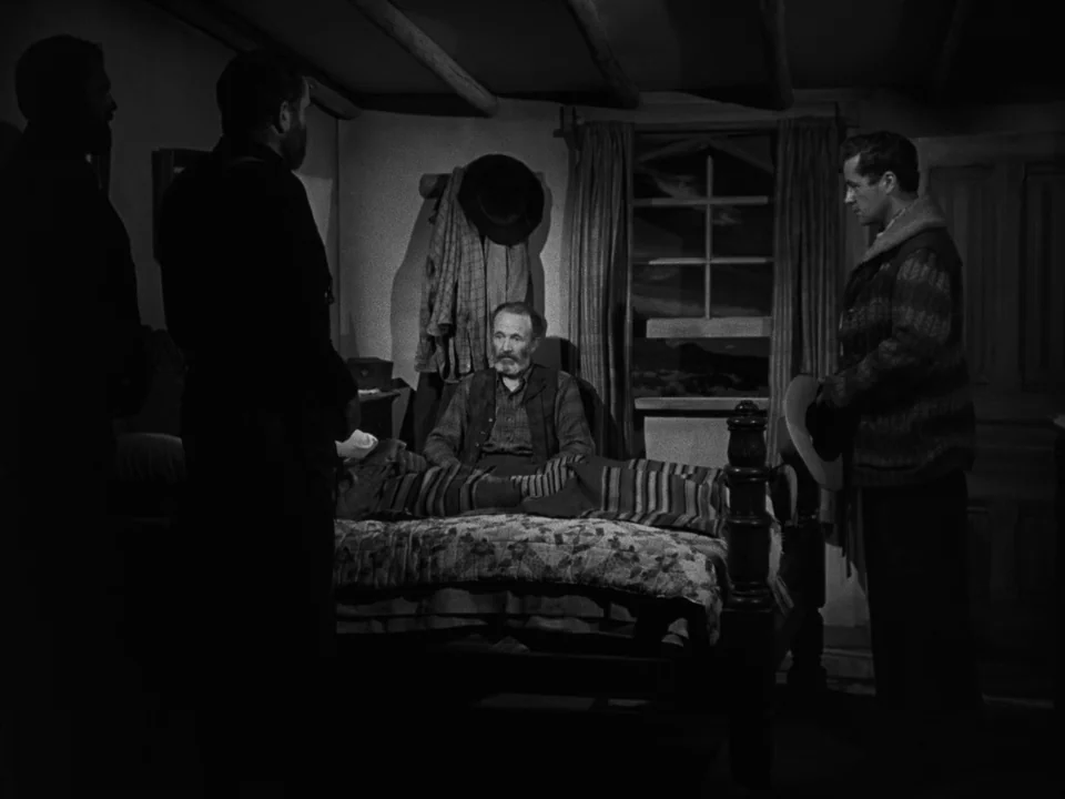 My Darling Clementine (1946) movie still: medium — A rustic cabin interior features wood-paneled walls and a window looking out onto darkness. A…