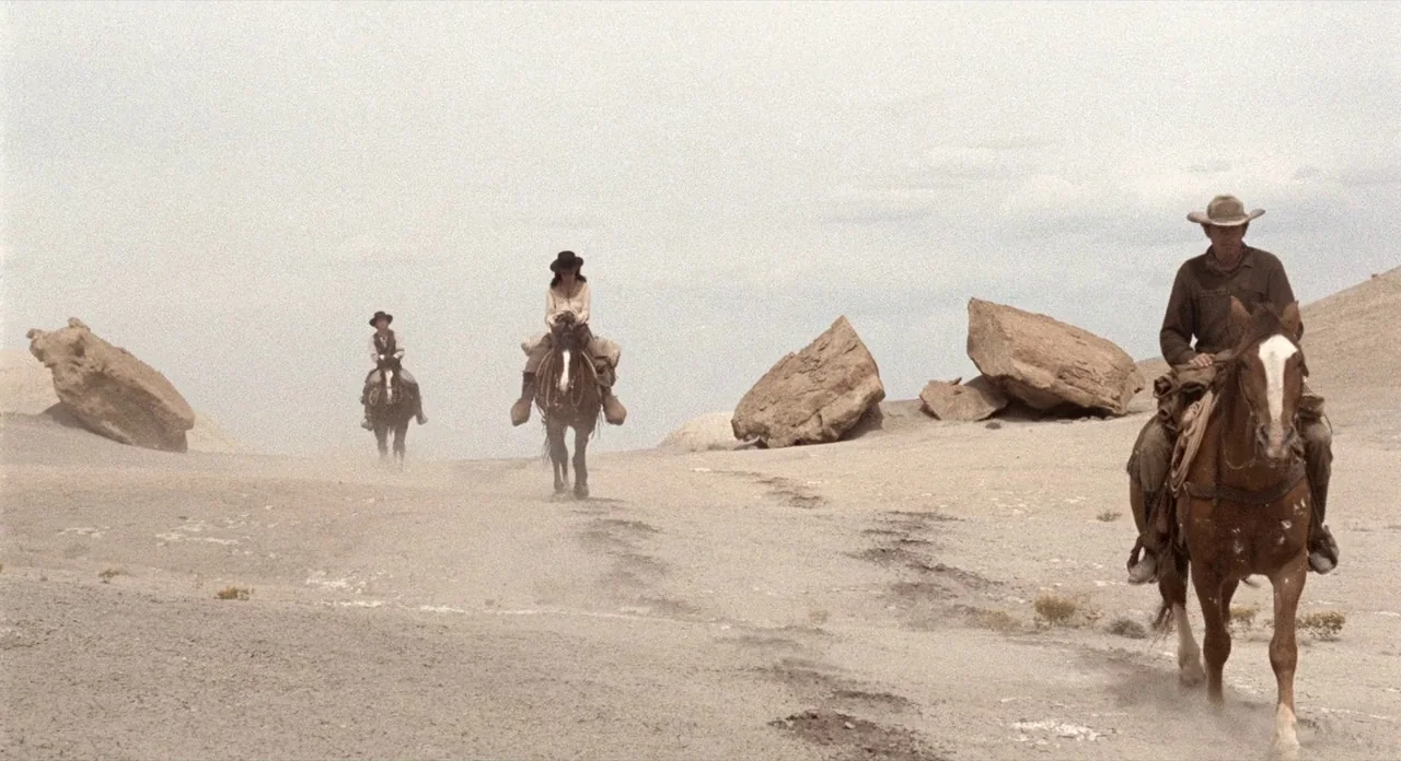 The Shooting (1966) movie still: wide — A vast, dusty desert terrain is punctuated by large scattered boulders and rocky outcrops. Three figures on…