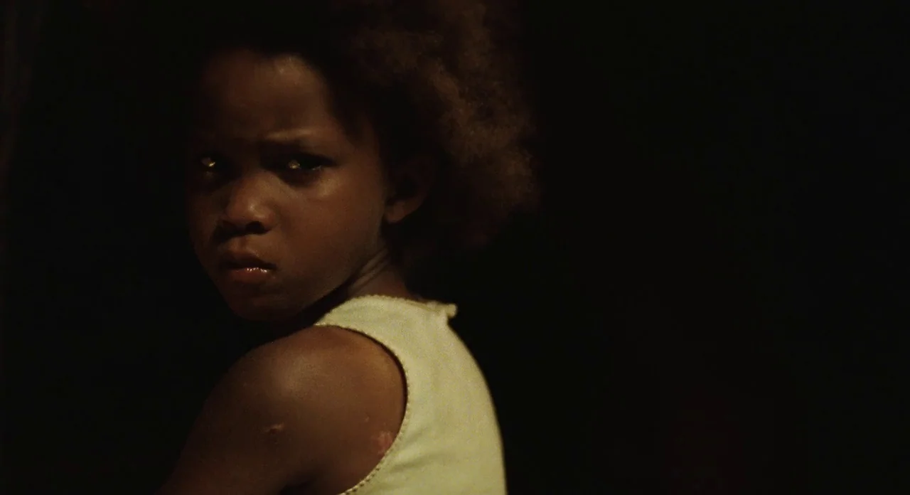 Beasts Of The Southern Wild (2012) movie still: closeup — A child is positioned in a dark room with minimal background detail visible. The child…