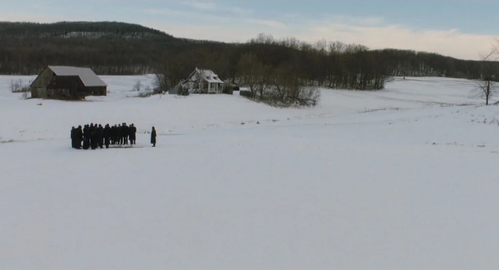The Fountain (2006) movie still: wide — A vast, snow-covered rural landscape features a distant barn and a small farmhouse structure. A small,…
