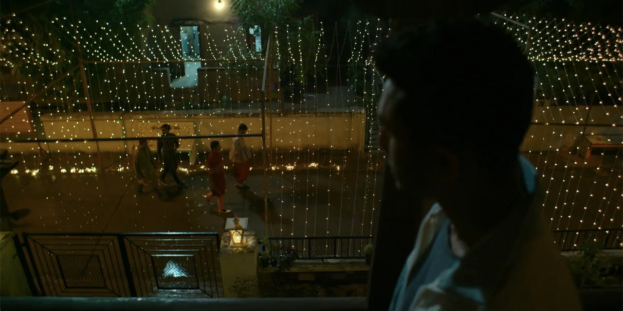Maja Stoneface (1996) movie still: medium — A night view from an elevated position looking down onto a paved courtyard area. Several people walk…