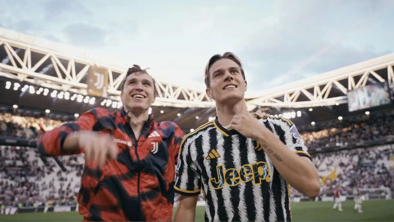 FRAGILE - The story of Nicolò Fagioli (2024) movie still: medium — A vast professional sports stadium filled with spectators on a bright day. Two…