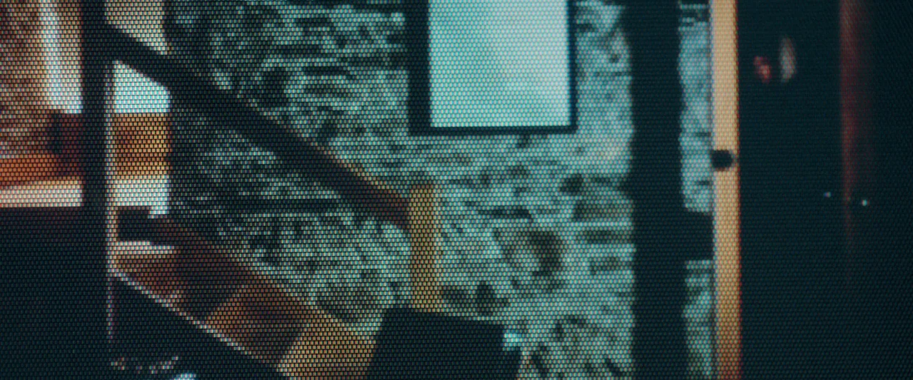 Oddity (2024) movie still: establishing — An interior space appears with a visible digital grid overlay and scan lines. The composition shows…