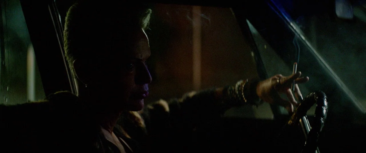 Triple 9 (2016) movie still: medium — The interior of a moving vehicle at night with dark surroundings. A man sits behind the steering wheel while…
