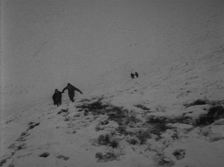 My Night At Maud’s (Ma Nuit Chez Maud) (1969) movie still: wide — A steep, snow-covered mountainside stretches upwards into the hazy distance. Two…