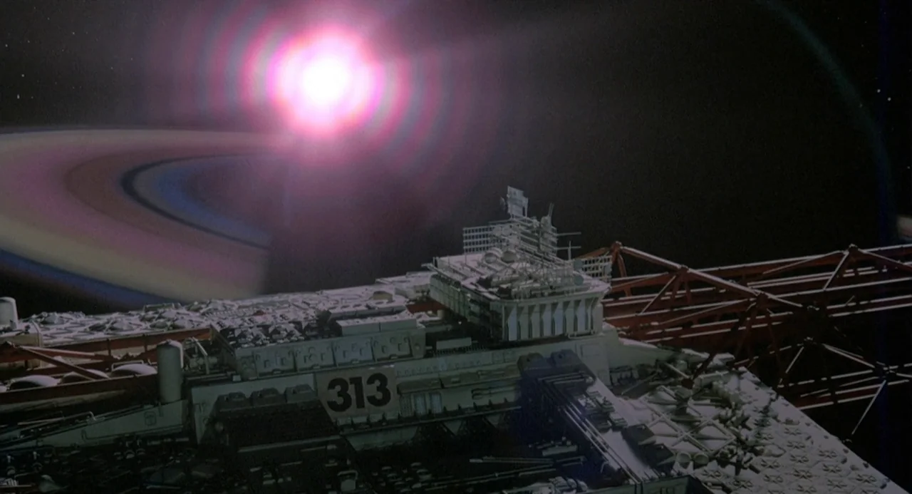 Silent Running (1972) movie still: wide — A detailed model spaceship floats in the dark expanse of deep space. A massive planetary ring and a…