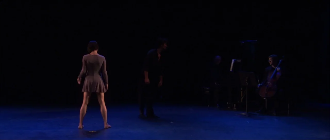 El acto (1989) movie still: wide — A dark stage area with a blue-lit floor and black background curtains. Two dancers stand in the center while a…
